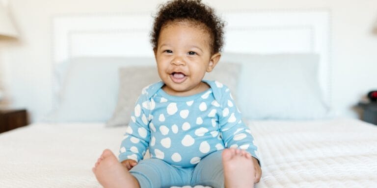 baby sitting up on bed - activities for 8-month-old