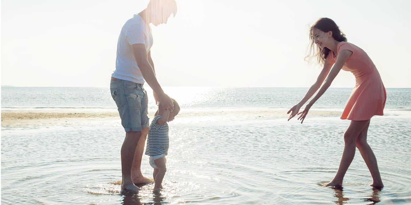 parents and baby playing in the ocean- spring break destinations for families