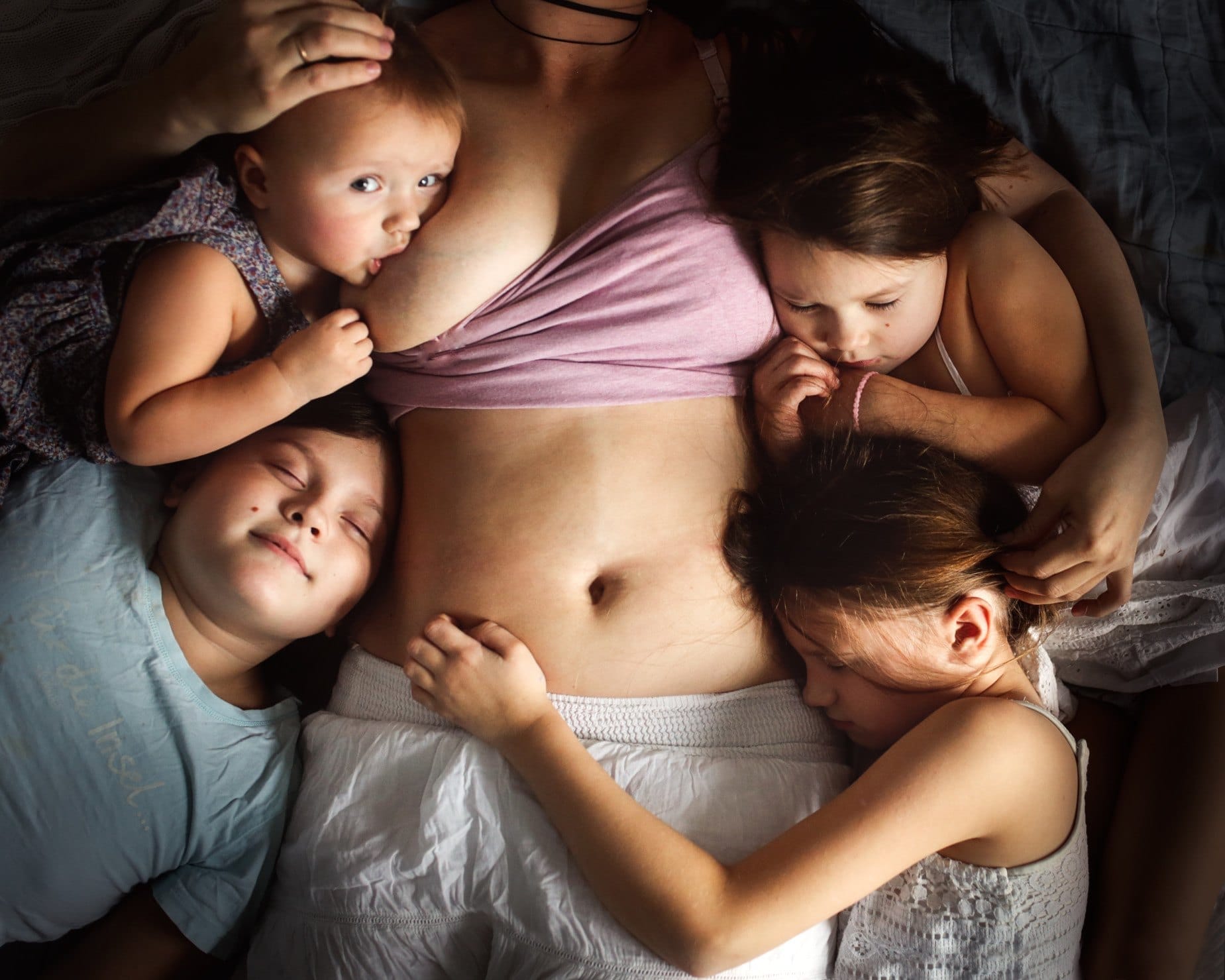 mom breastfeeding a baby while holding three other children