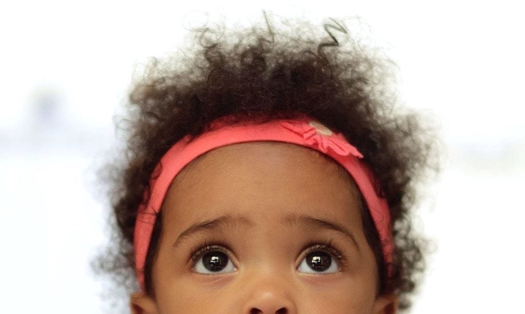 little girl wearing a headband and looking up