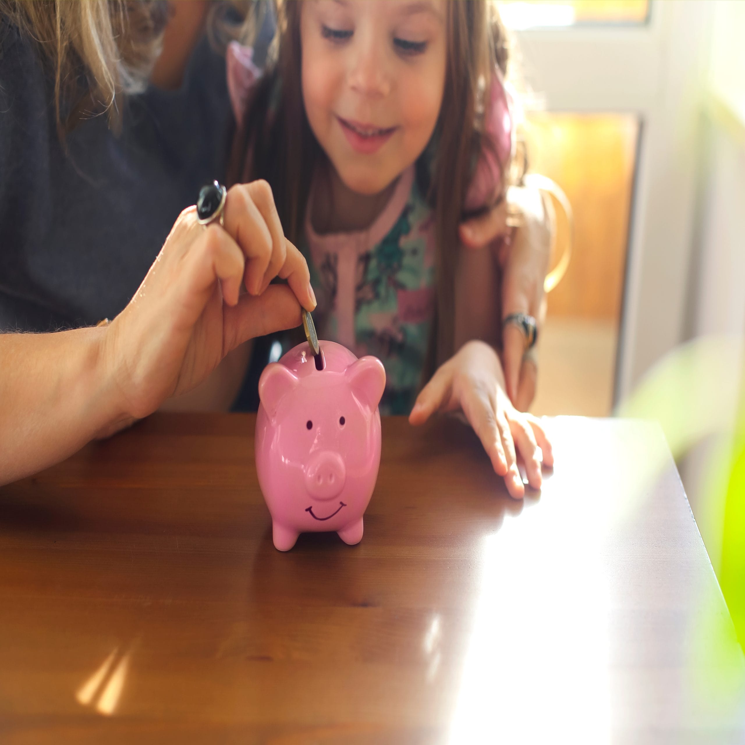 Mom and daughter savings plan with piggy bank