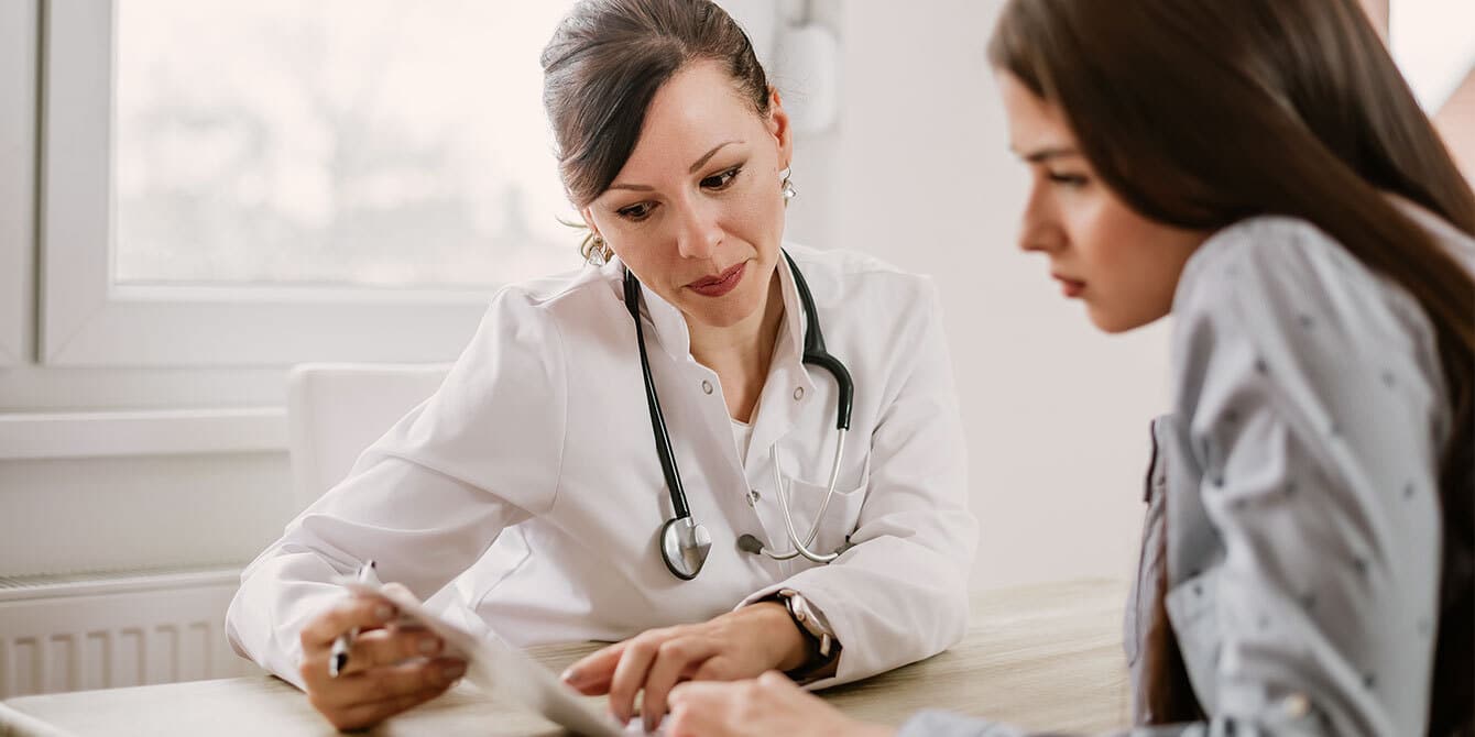 Woman at preconception checkup talking with her doctor - preconception checkup questions to ask your doctor