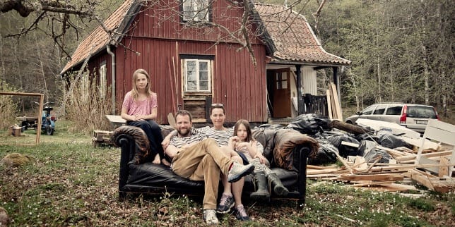 a group of people sitting on a couch in front of a red house