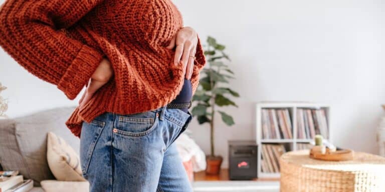 pregnant woman in jeans holding belly - hidden pregnancy signs