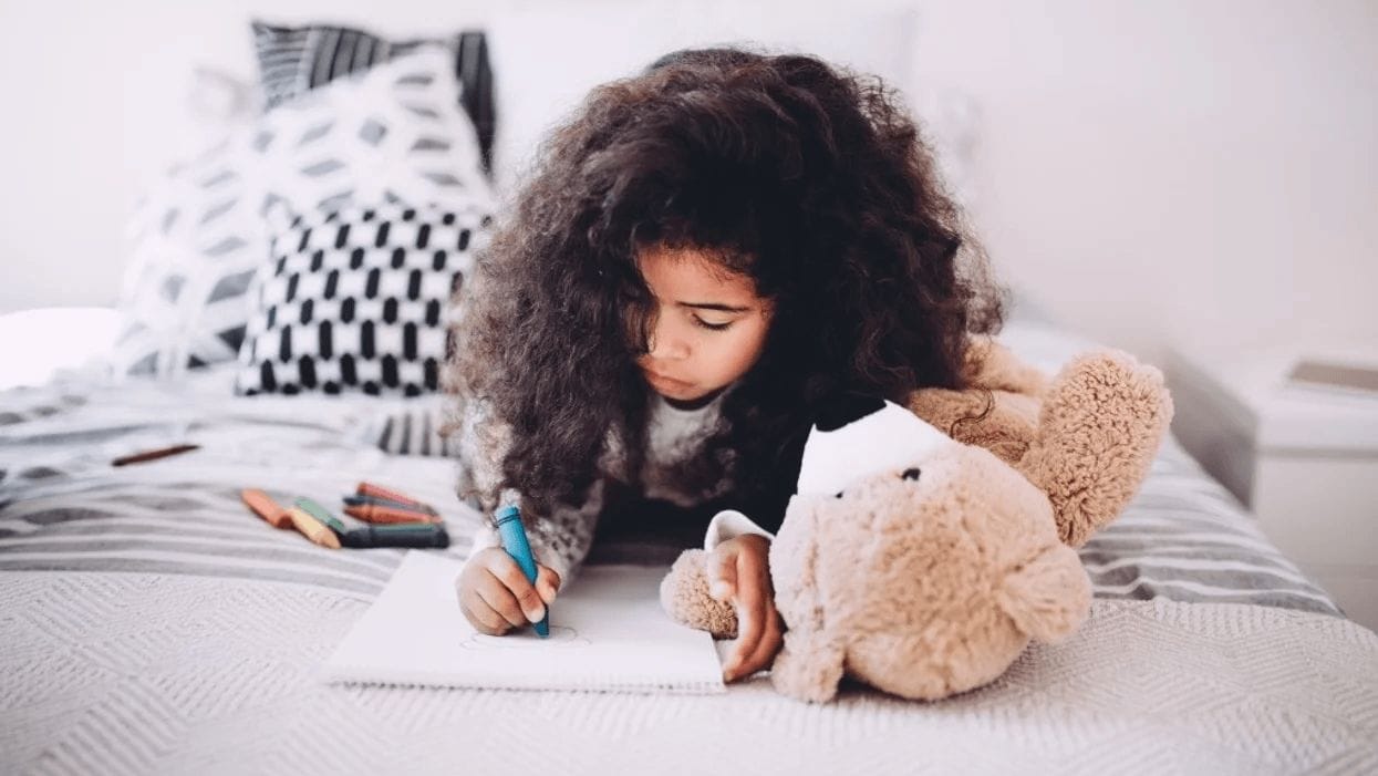 little girl coloring on her bed