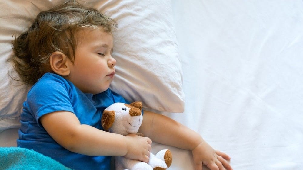 a baby sleeping with a stuffed animal