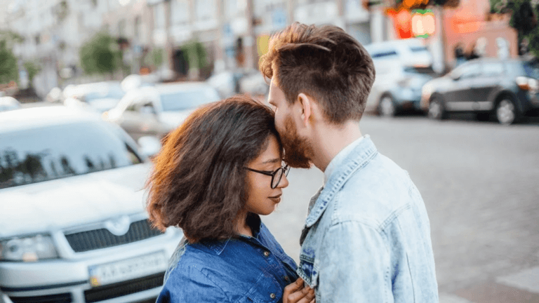 man kissing woman on forehead