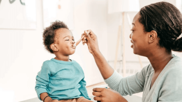 mom feeding toddler yogurt