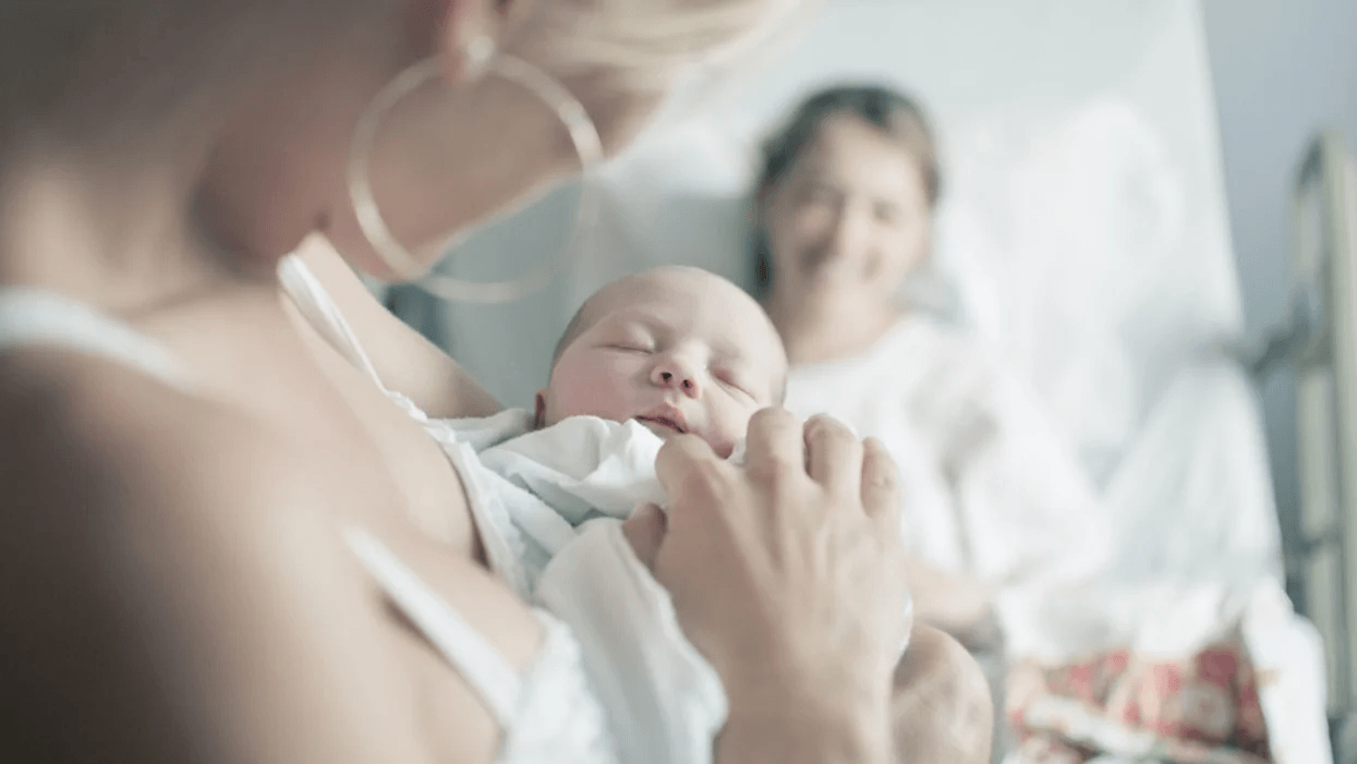 woman holding baby while mom rests in the background