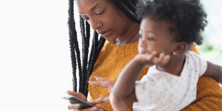 mom holding toddler while on her phone