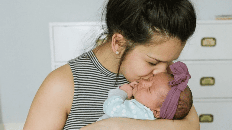 mom kissing newborn baby