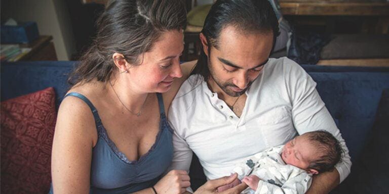 man and woman looking at a baby