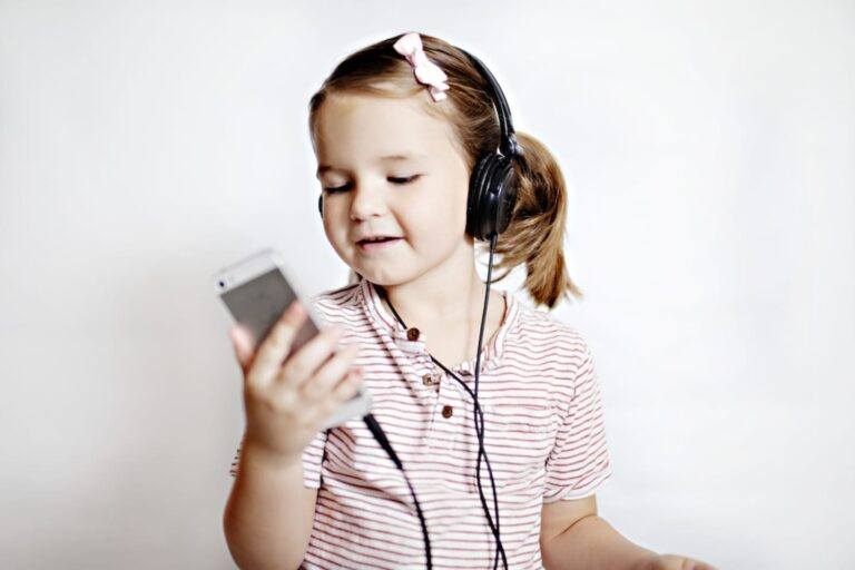 child wearing headphone, listening and looking at her phone