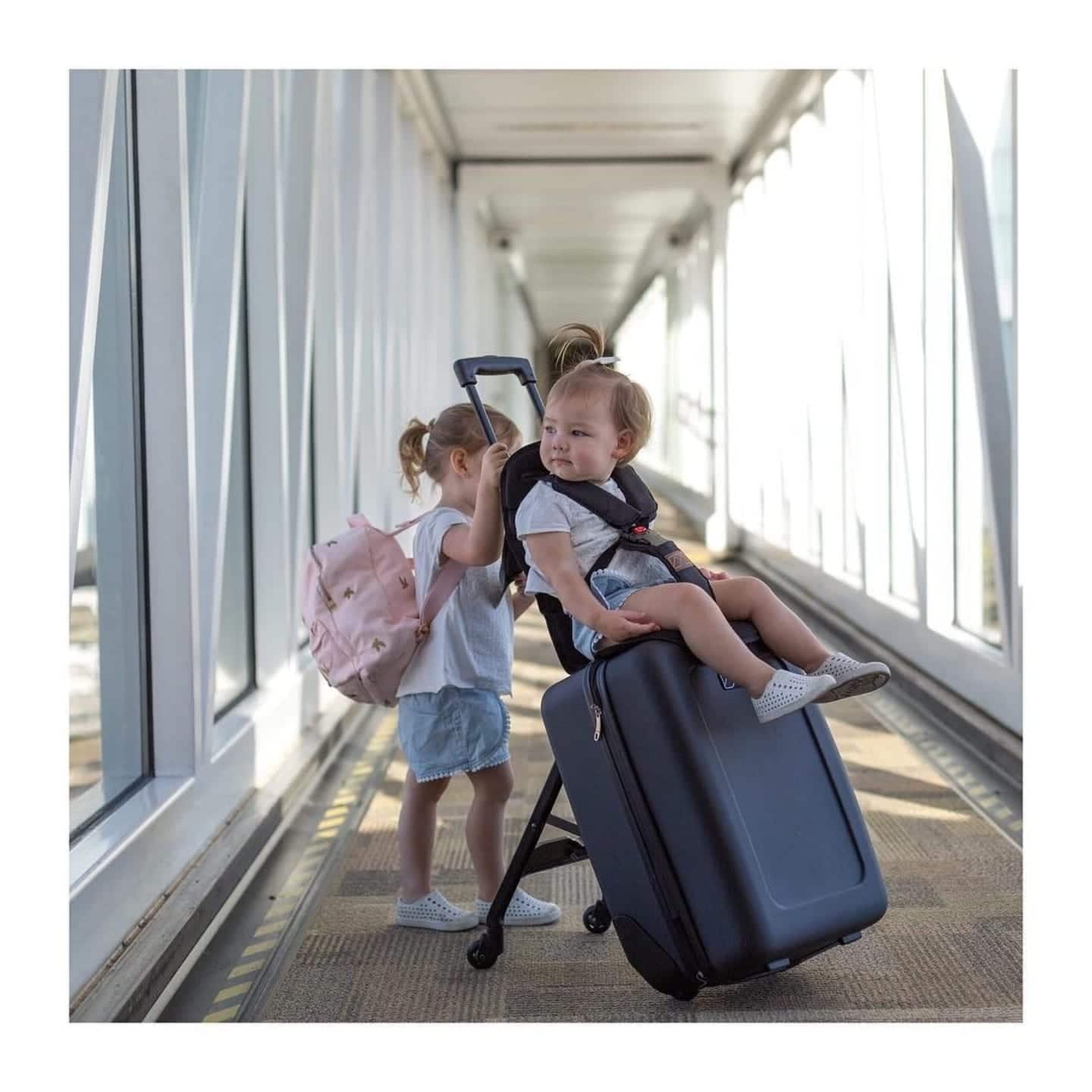 baby riding a suitcase at the airport, one of motherly's best products for baby's first flight