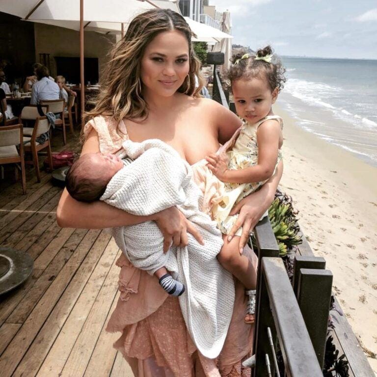 Chrissy Teigen carrying both of her children