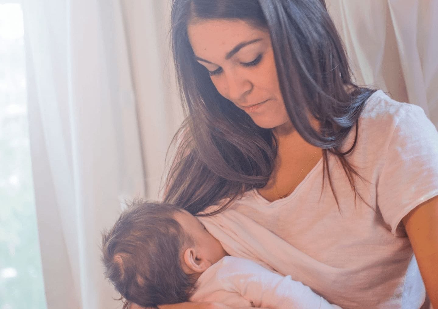 woman breastfeeding baby under her shirt- what I didn't know about breastfeeding