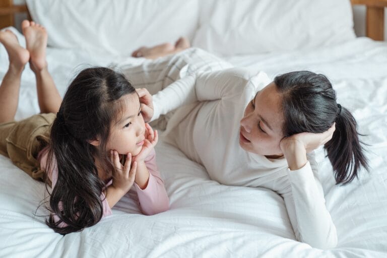 mom and daughter talking on bed