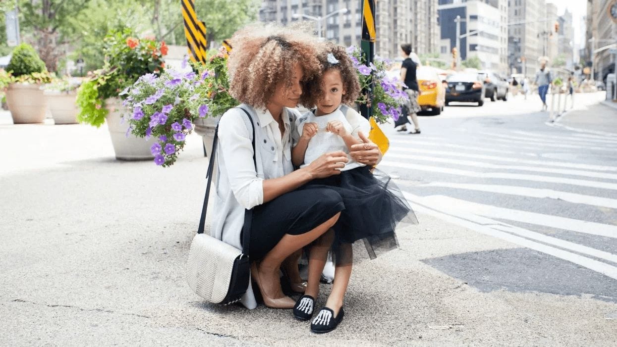 mom holding little girl on the sidewalk