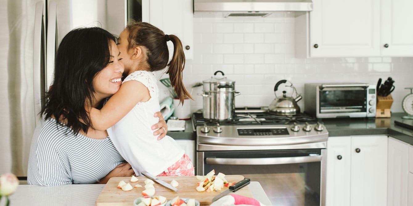 mother and daughter hugging in the kitchen- how to raise grateful children