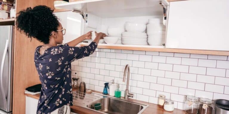 woman putting plates away- how to organize your home