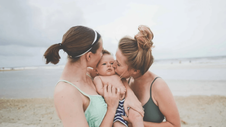 Two women kissing a little boy on the cheeks