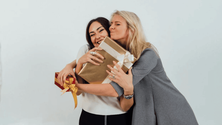 two women hugging while holding wrapped presents