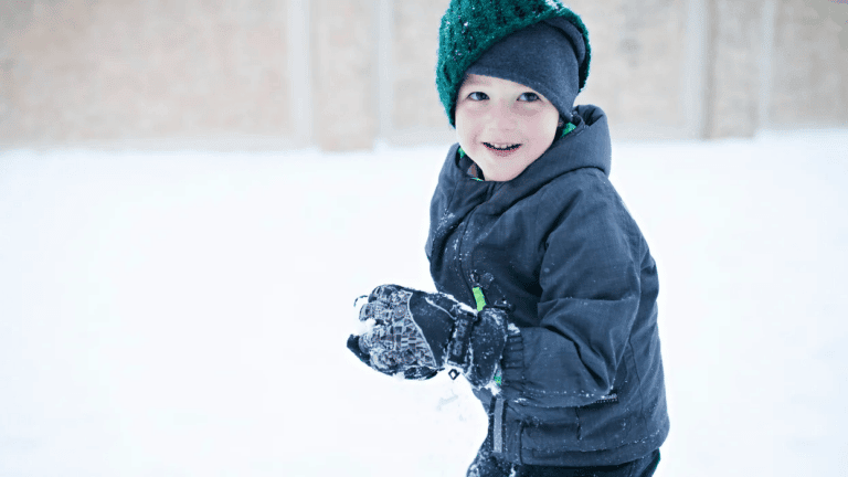 little boy making a snowball