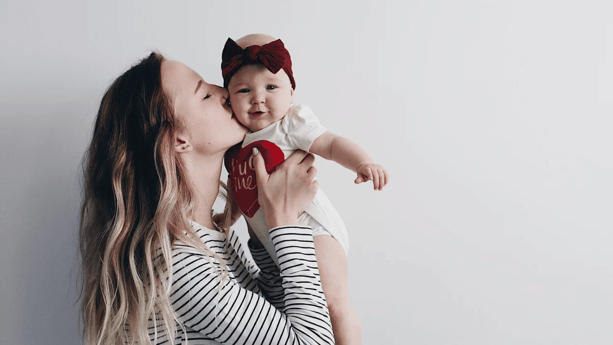 mom kissing baby girl on the cheek