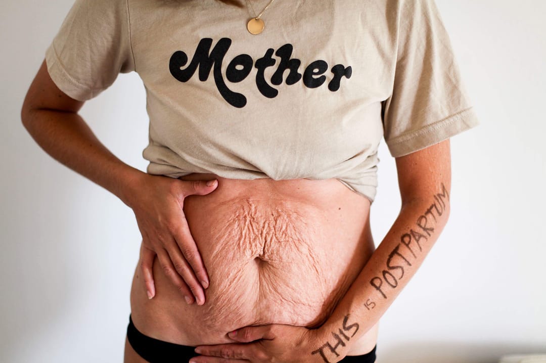 woman wearing a mother shirt holding her stomach-postpartum body