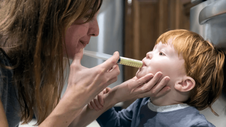 mom giving toddler medicine in a syringe