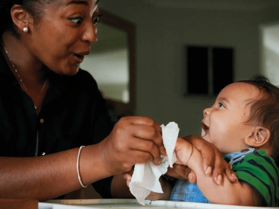 mom using baby wipe to wipe off baby hands