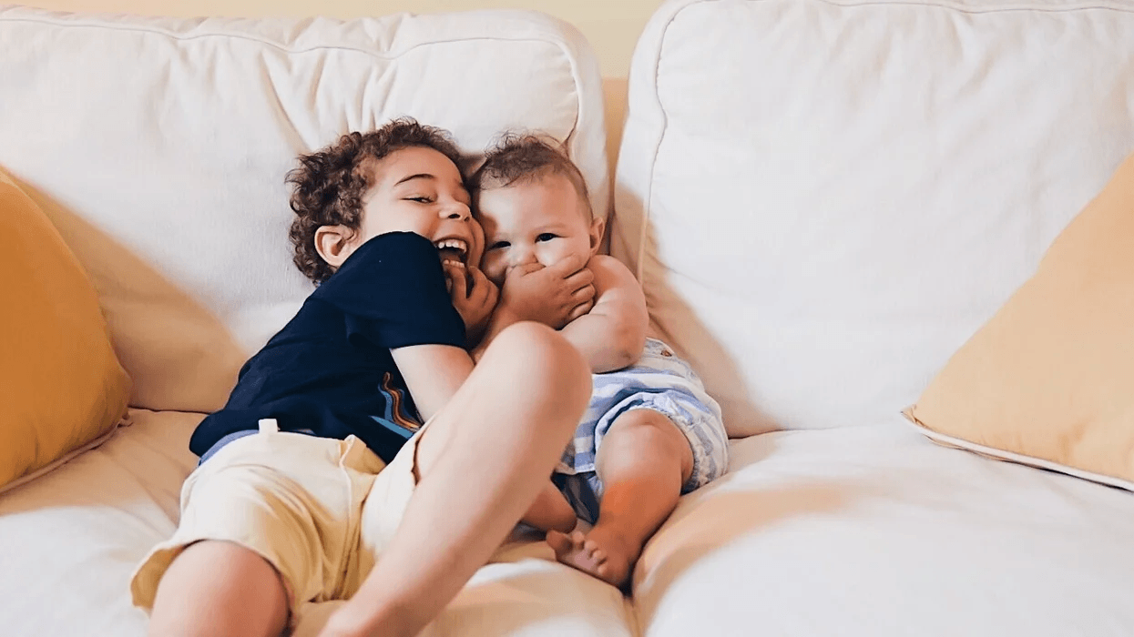 toddler and baby siblings hugging on the couch- don't you ever grow up