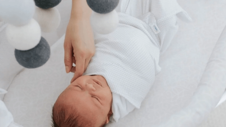 baby wearing a sleep sack in a crib