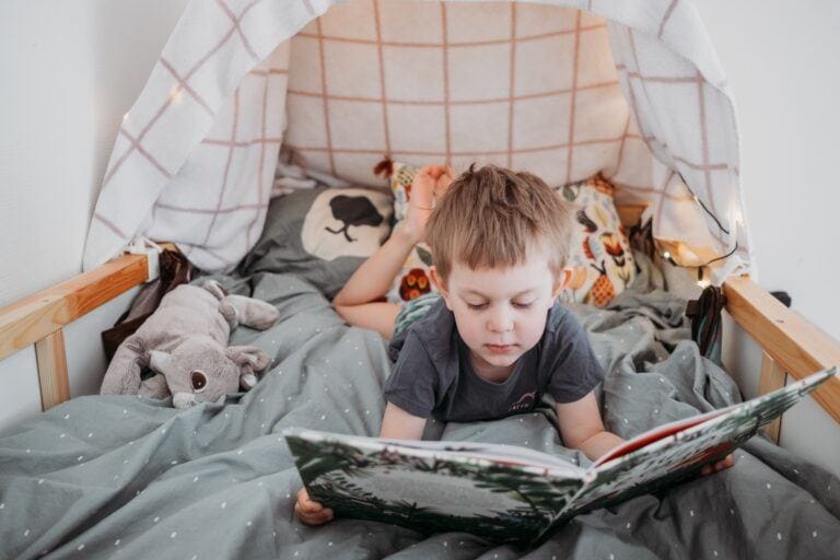 little boy reading in bed