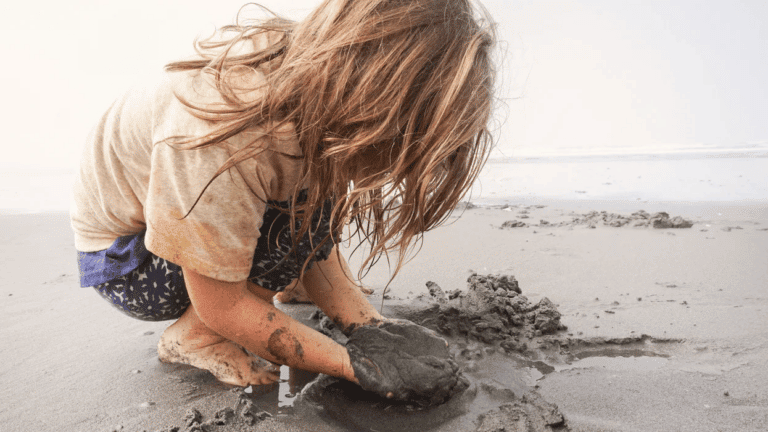 little kid playing with wet sand