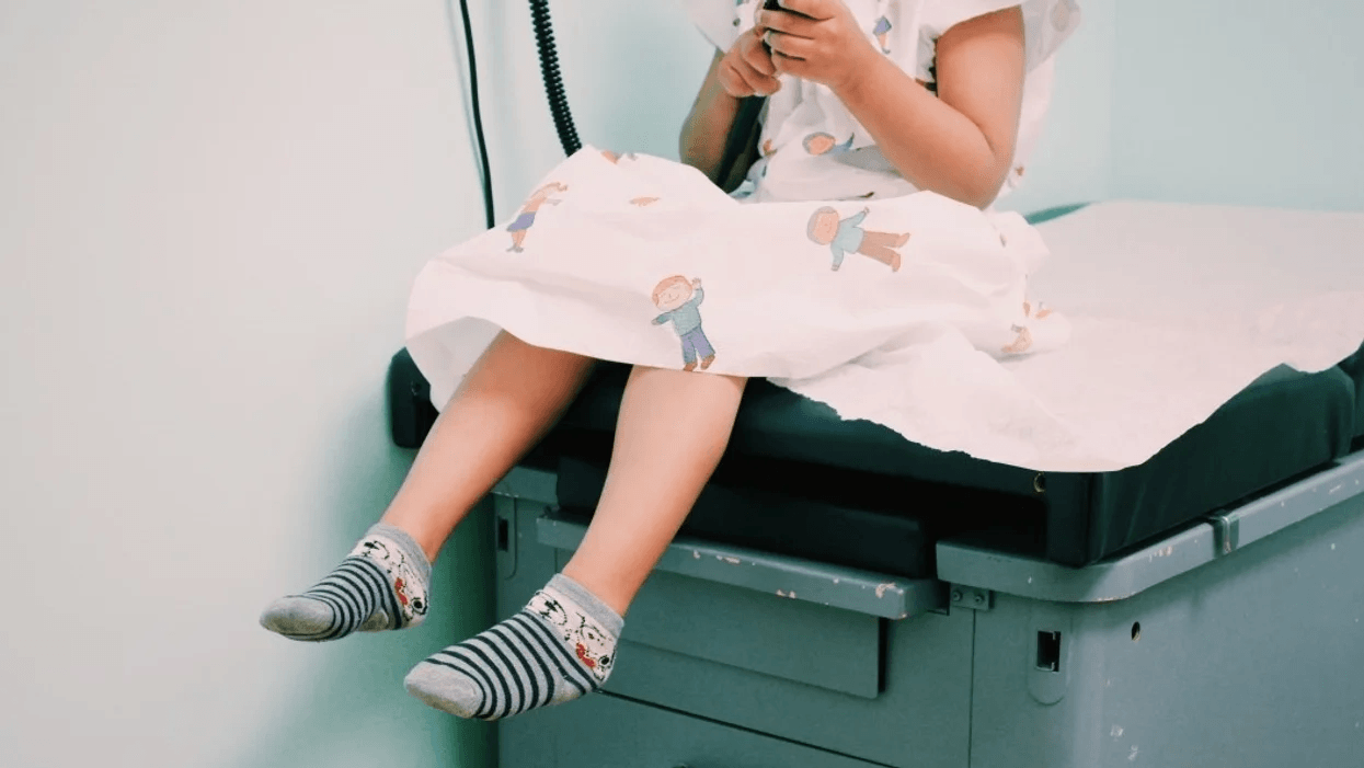 child's feet hanging off a doctors bench