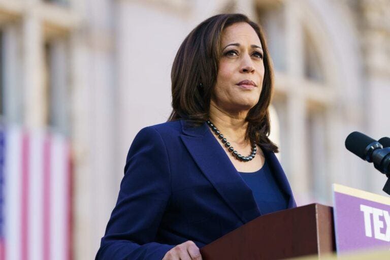 kamala harris standing at podium wearing blue suit