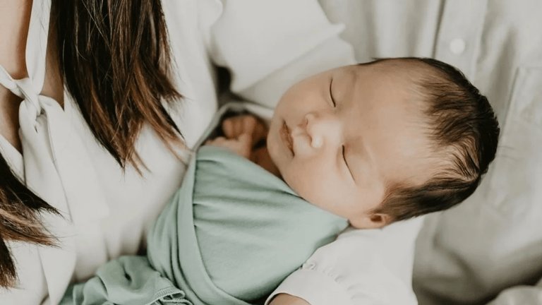 mom holding swaddled, sleeping baby