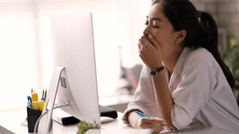 woman yawning at computer screen