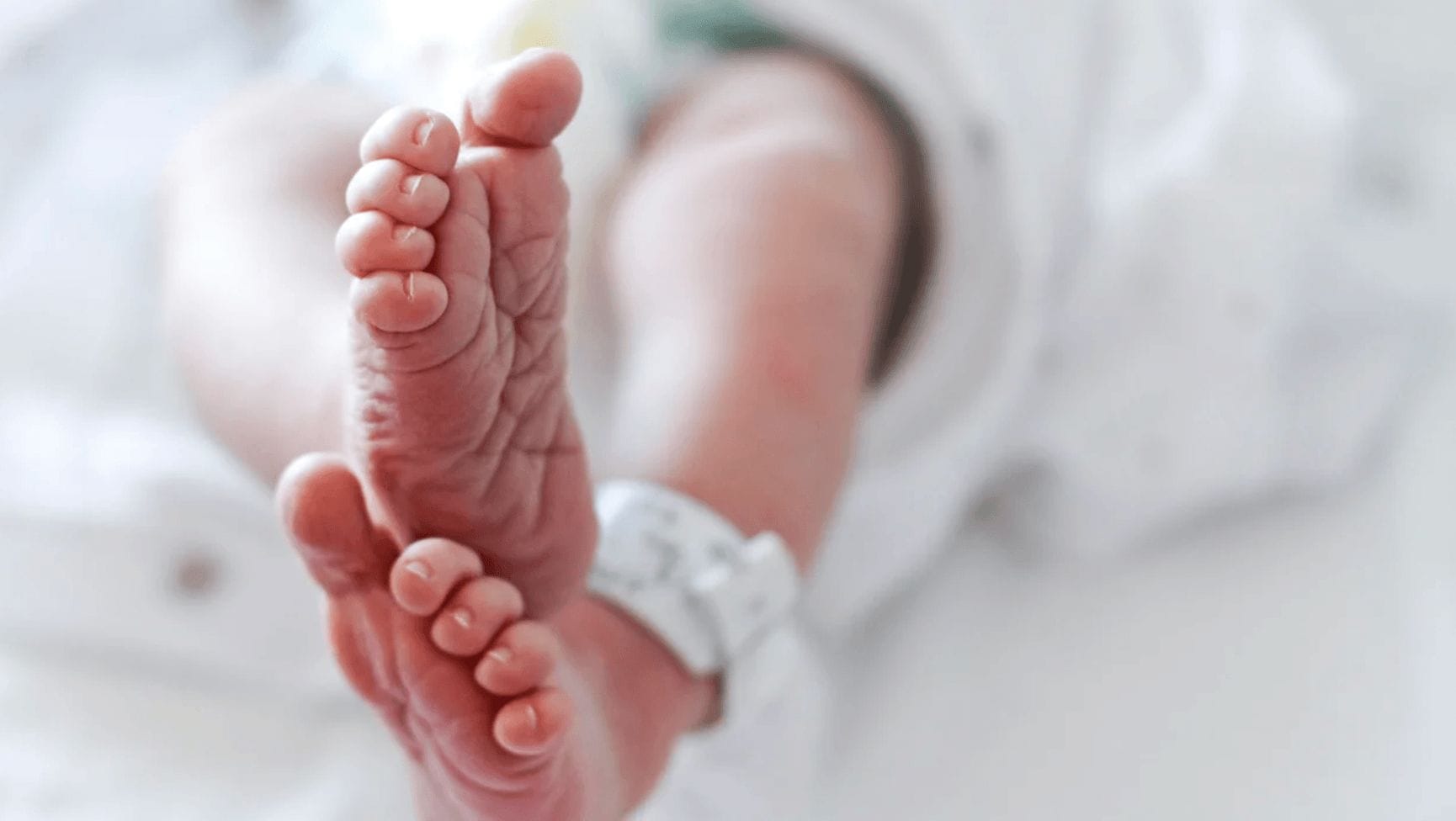 baby feet with a hospital blanket on the ankle