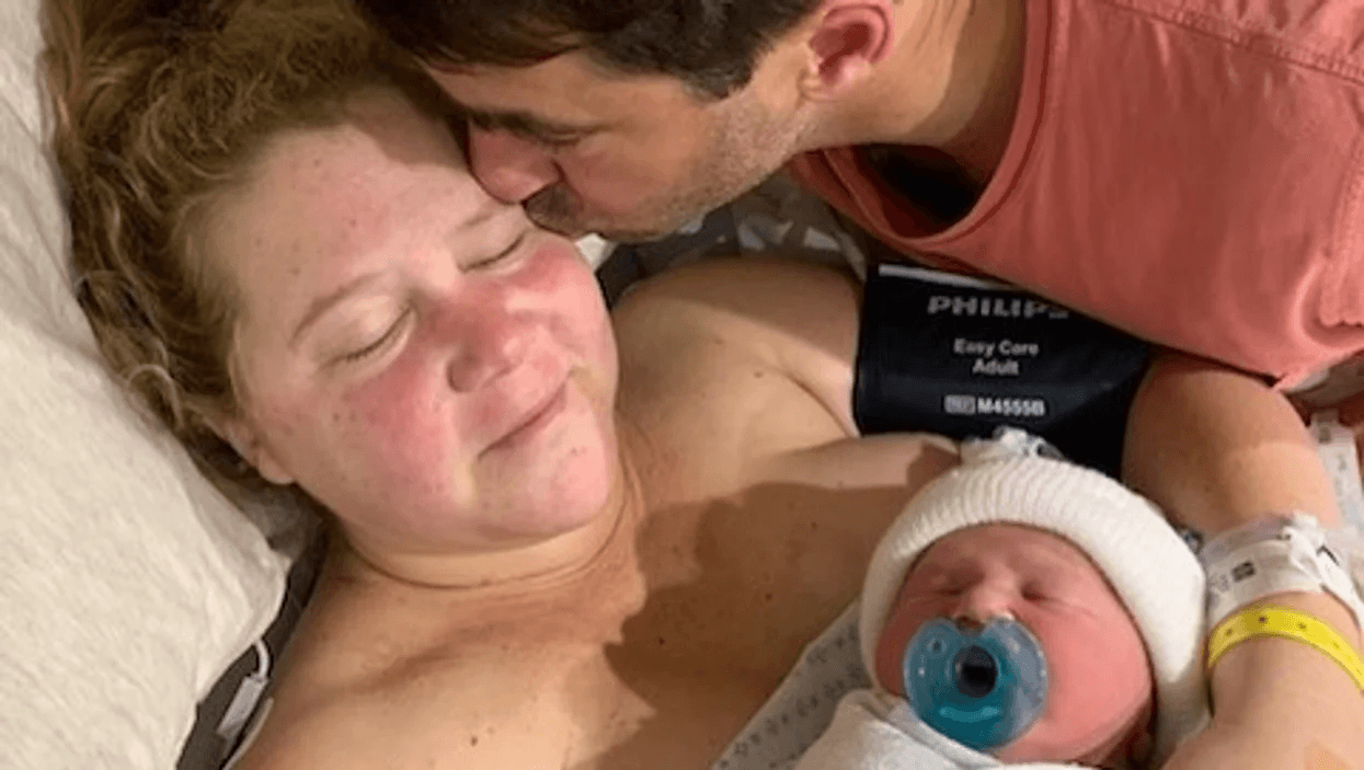 Amy Schumer holding her new baby while husband kisses her head