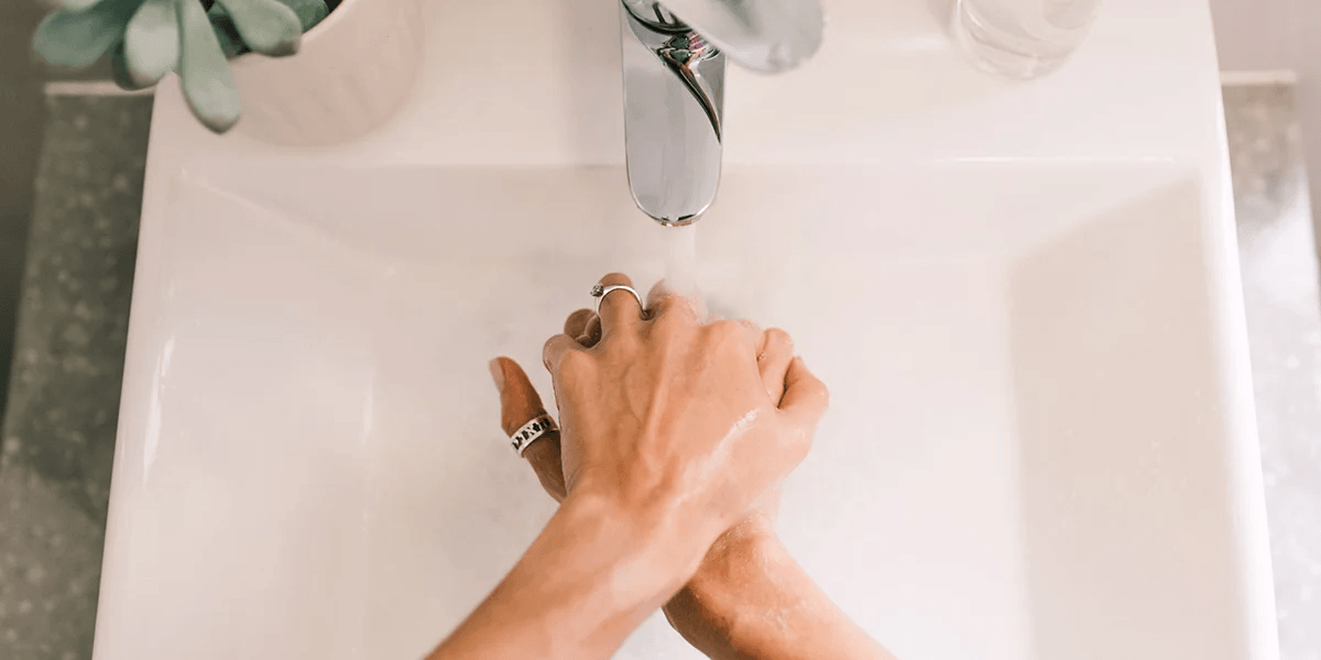 woman washing hands under sink