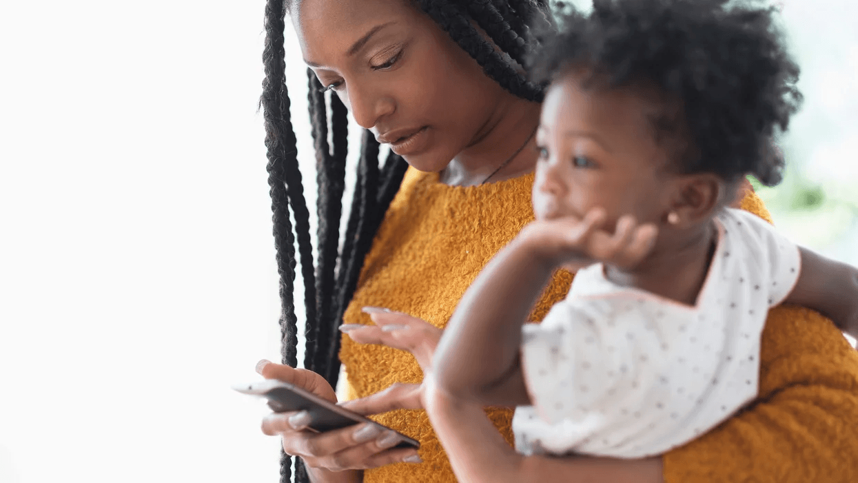 mom holding daughter while on phone