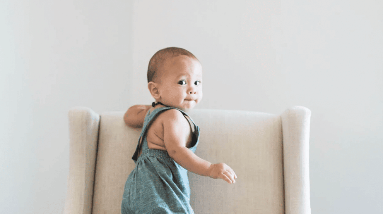 baby climbing up on nursery glider