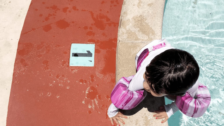 little girl wear a swim vest outside a pool