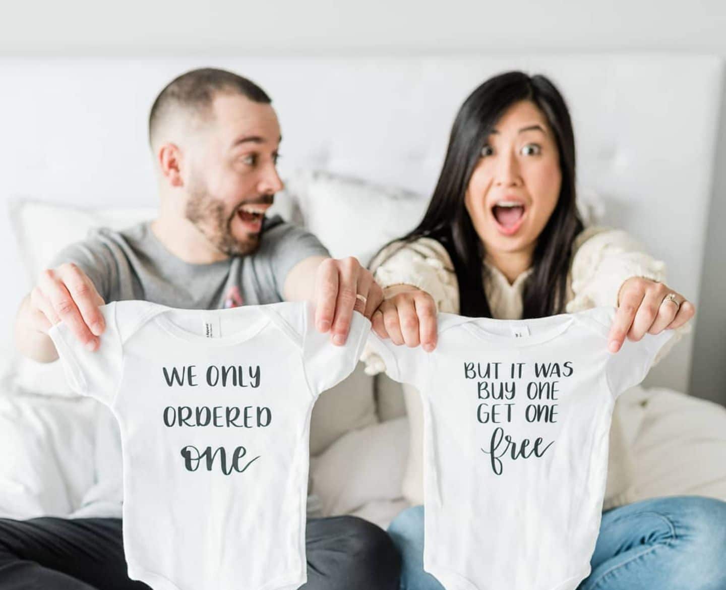 parents holding up onesies for a pregnancy announcement ideas