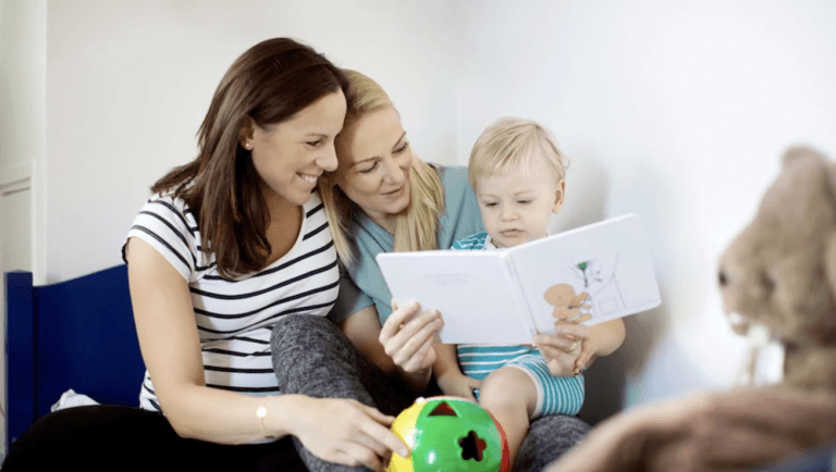 two moms reading a book to a toddler