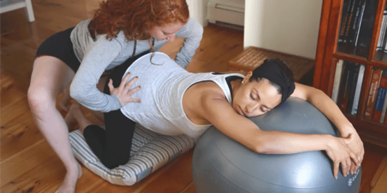 midwife helping a pregnant woman on a birthing ball during labor