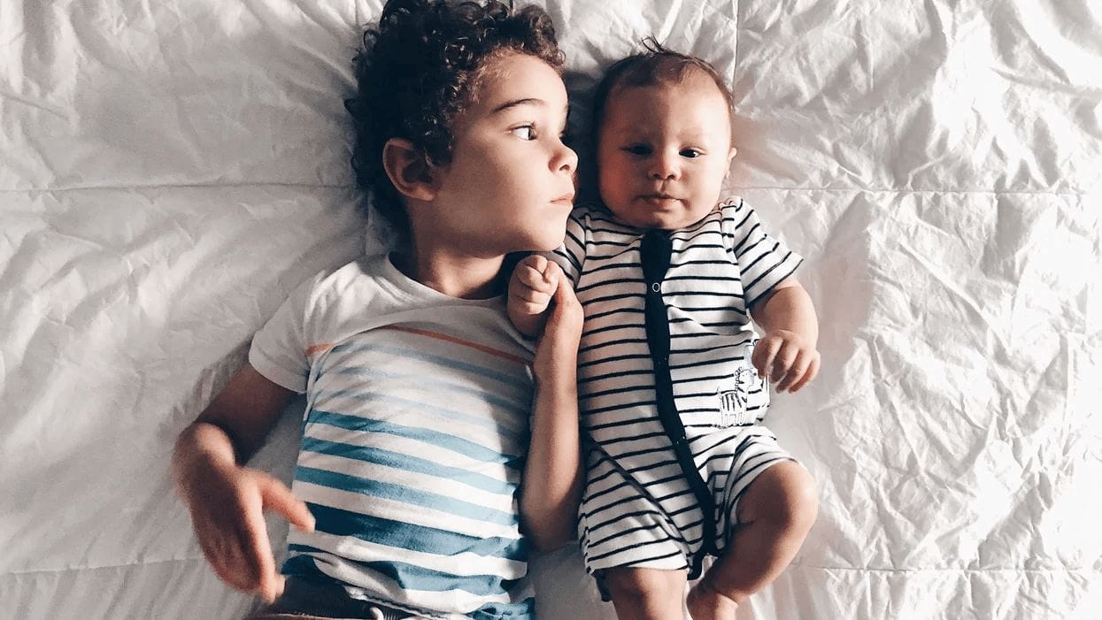 two siblings laying on a bed