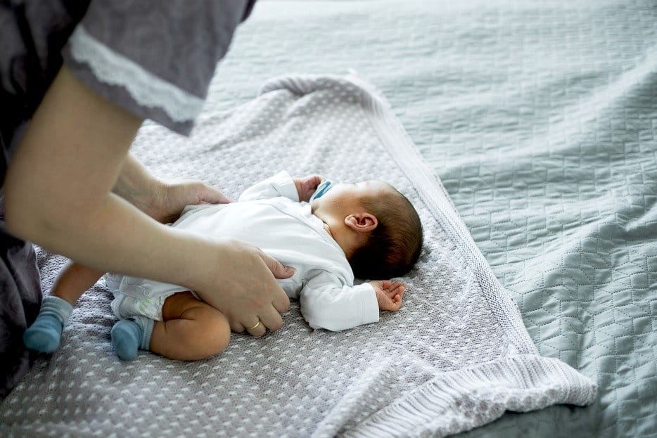 mom playing with a newborn baby on the floor